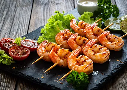 Garnelen-Spieße gegrillt angerichtet auf einem schwarzen Teller